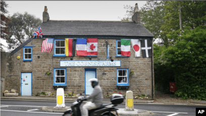 A motorcyclist passes in front of the club adorned with the flags of the G-7 countries (Cornwall, England, June 9, 2021)