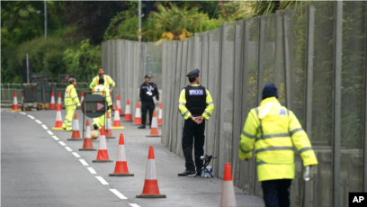Police officers stand guard near fence surrounding Tregenna Castle, Cornwall, England (June 9, 2021)